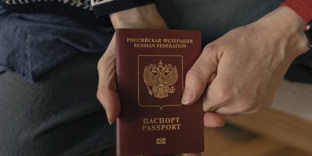 Russian Marina shows her Russian passport as she poses for a photo in a hostel of Belgrade.