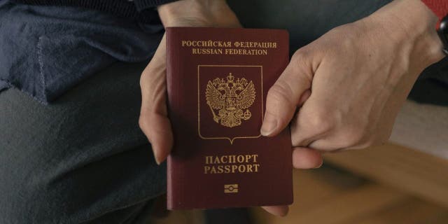 Russian Marina flashes her Russian passport as she poses for a photo in a Belgrade hostel.