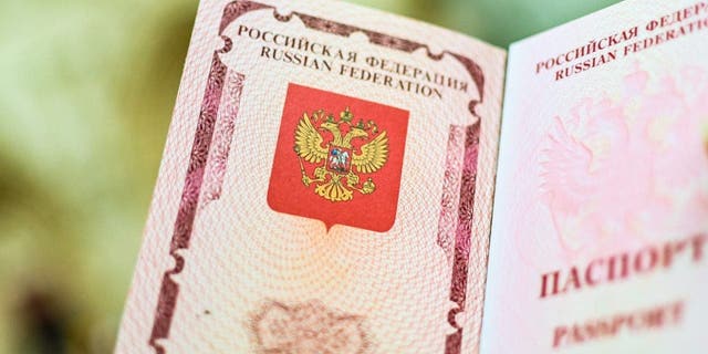The emblem of the Russian Federation drawn on the passport.  A woman shows her Russian passport.