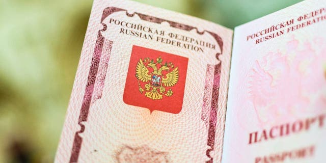 The emblem of the Russian Federation drawn in the passport. A woman shows her Russian passport.