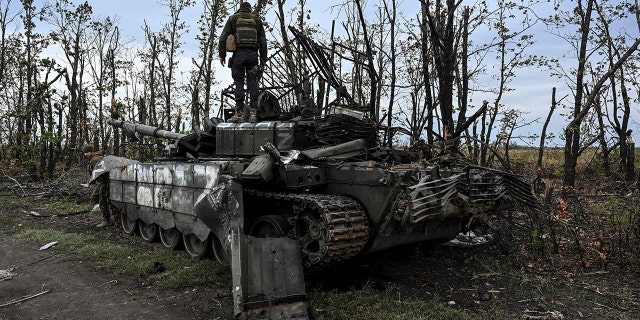 This photograph taken on September 11, 2022, shows a Ukranian soldier standing atop an abandoned Russian tank near a village on the outskirts of Izyum, Kharkiv Region, eastern Ukraine.