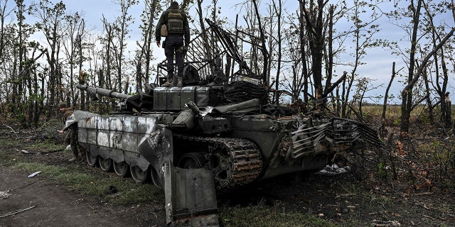 This photograph taken on September 11, 2022, shows a Ukranian soldier standing atop an abandoned Russian tank near a village on the outskirts of Izyum, Kharkiv Region, eastern Ukraine. 