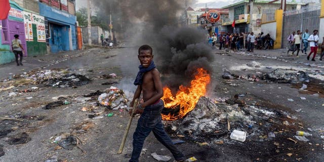 A man walks past a burning barricade during a protest against Haitian Prime Minister Ariel Henry in Port-au-Prince, Haiti, Oct. 10, 2022.