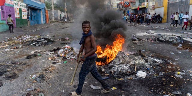 A man walks past a burning barricade during a protest against Haitian Prime Minister Ariel Henry in Port-au-Prince, Haiti, Oct. 10, 2022.