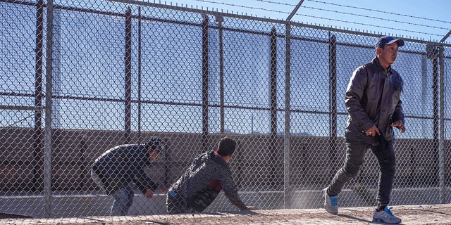 Migrants illegally cross into the United States via a hole in a fence in El Paso, Texas, on Dec. 22, 2022.