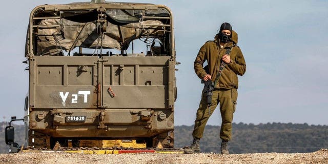 An Israeli soldier stands next to a truck at a position in the Israeli Golan Heights near the border with Syria on January 2, 2023.  Israeli missile strikes on the Syrian capital's airport on January 2 killed four people, including two soldiers, and closed the runways for several hours, a rights monitor said. 