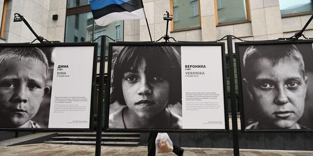 Un peatón pasa por "niños donbass" Una exposición de fotografías al aire libre frente al Consulado de Estonia en Moscú el 23 de enero de 2023.