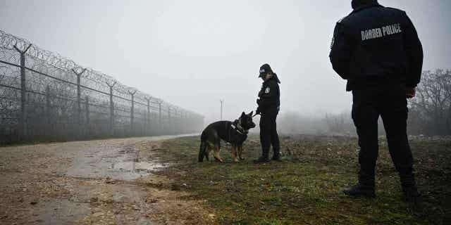 Bulgarian border police officers patrol with a dog in front of the border fence on the Bulgaria-Turkey border on Jan. 13, 2023. The anti-torture monitor in Europe decried border guards use of violence and dogs to humiliate migrants.