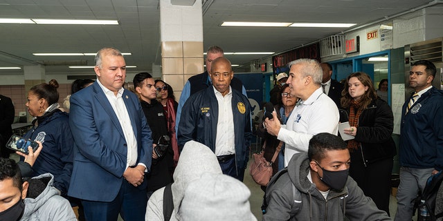 Mayor Eric Adams, center, seen helping to distribute donated food and clothing to families of asylum seekers in the city at Public School 20 Anna Silver School.  On Tuesday, he unveiled a blueprint for addressing the migrant crisis.