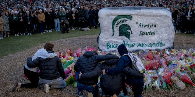 People embrace during the vigil at The Rock on Michigan State University's campus in East Lansing, Michigan on February 15, 2023. 