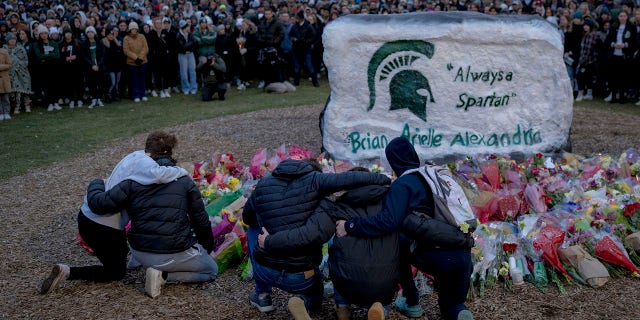 People embrace during the vigil at The Rock on Michigan State University's campus in East Lansing, Michigan on February 15, 2023. 