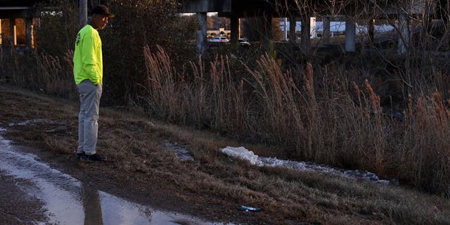 A contractor working for the city of Jackson, Mississippi, watches as water from a damaged main runs along McLaurin Road on Dec. 29, 2022.