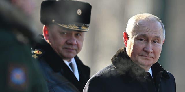 Russian President Vladimir Putin, right, and Russian Defense Minister Sergei Shoigu, left, attend a wreath-laying ceremony at the Eternal Flame and Tomb of the Unknown Soldier in the Alexander Garden during an event marking the Defender of the Fatherland Day in Moscow.