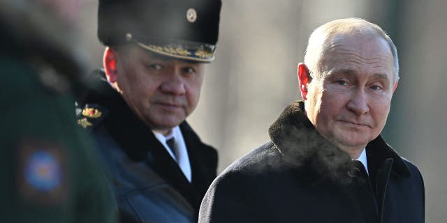 Russian President Vladimir Putin, right, and Russian Defense Minister Sergei Shoigu, left, attend a wreath-laying ceremony at the Eternal Flame and Tomb of the Unknown Soldier in the Alexander Garden during an event marking the Defender of the Fatherland Day in Moscow.