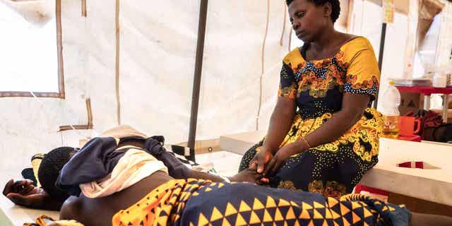 A woman holds the hand of her son at a temporary cholera treatment center at a hospital in Lilongwe on Feb. 21, 2023. A World Health Organization official is urging more support for countries suffering from cholera outbreaks.