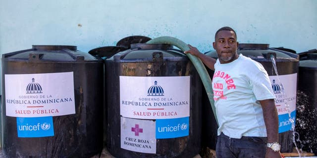 A worker from the state drinking water company refills containers installed by the Public Health Ministry due to a cholera outbreak in Santo Domingo, on Feb. 9, 2023.