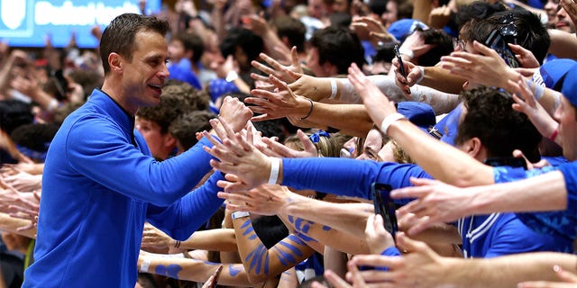 Duke Blue Devils head coach Jon Scheyer high-fives the Cameron Crazies after their game against the NC State Wolfpack at Cameron Indoor Stadium on February 28, 2023 in Durham, North Carolina.  Duke won 71-67. 