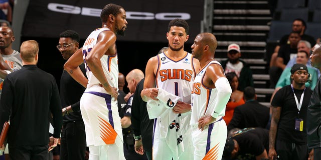 Kevin Durant, 35 numara, Phoenix Suns'tan 1 numara Devin Booker ve 3 numara Chris Paul ile 1 Mart 2023'te Charlotte, Kuzey Carolina'da Spectrum Center'da Charlotte Hornets'e karşı oynanan bir maçta konuşuyor.