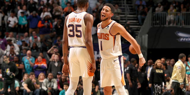 Devin Booker, #1, and Kevin Durant, #35 of the Phoenix Suns, celebrate during the game against the Charlotte Hornets on March 1, 2023 at Spectrum Center in Charlotte, North Carolina.