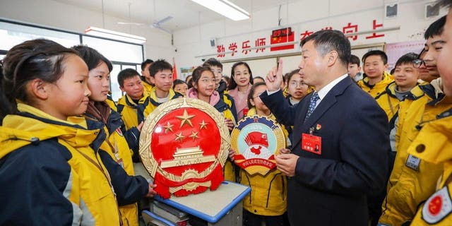 Geng Huaiqing, wakil Kongres Rakyat Nasional, menjelaskan "dua sesi" kepada siswa di distrik Huaian, Kota Huai'an, Provinsi Jiangsu, China Timur, 3 Maret 2023.