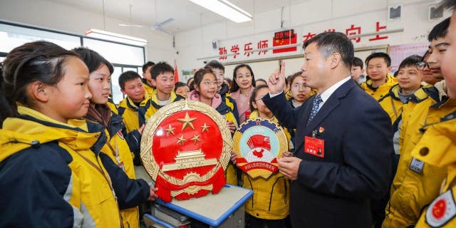 Geng Huaiqing, a deputy to the National People's Congress, explains the "two sessions" to students in Huaian district, Huai 'an City, East China's Jiangsu Province, March 3, 2023.