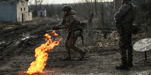 Ukrainian servicemen light a fire with gunpowder to get warm near the city of Bakhmut in the region of Donbas on March 5, 2023.