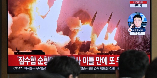 People stand near a television showing a news broadcast with file footage of a North Korean missile test, at a railway station in Seoul on March 14, 2023.