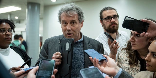 Sen. Sherrod Brown, D-Ohio, speaks to reporters in the Senate subway on his way to a vote at the U.S. Capitol March 14, 2023 in Washington, D.C.