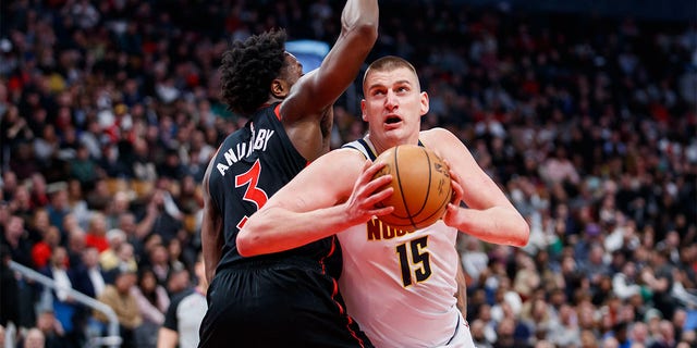 Nikola Jokic of the Denver Nuggets goes to the net around OG Anunoby of the Raptors at Scotiabank Arena on March 14, 2023, in Toronto, Canada.