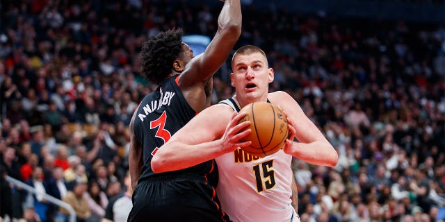 Nikola Jokic of the Denver Nuggets goes to the net around OG Anunoby of the Raptors at Scotiabank Arena on March 14, 2023, in Toronto, Canada.