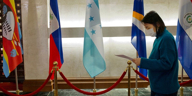 A woman walks past a Honduras flag at Taiwans Ministry of Foreign Affairs in Taipei. Honduras will establish diplomatic relations with China, President Xiomara Castro said Tuesday, without specifying if that means cutting ties with Taiwan.
