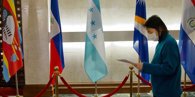 A woman walks past a Honduras flag at Taiwans Ministry of Foreign Affairs in Taipei. Honduras will establish diplomatic relations with China, President Xiomara Castro said Tuesday, without specifying if that means cutting ties with Taiwan.