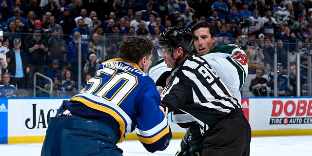 Marc-Andre Fleury, #29 of the Minnesota Wild, attempts to get physical with Jordan Binnington, #50 of the St. Louis Blues but is stopped by linesman Dan Kelly, #98, at the Enterprise Center on March 15, 2023, in St. Louis, Missouri. 