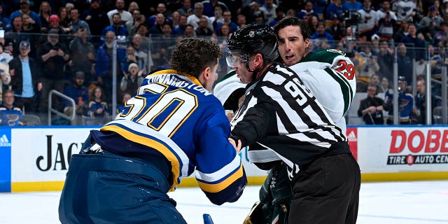 Marc-Andre Fleury, #29 of the Minnesota Wild, tries to make contact with Jordan Binnington, #50 of the St. Louis Blues, but is stopped by linesman Dan Kelly, #98 at the Enterprise Center on March 15, 2023, in St. Louis, Missouri. 