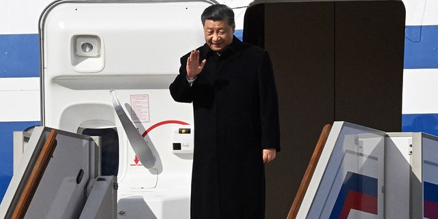 El presidente chino, Xi Jinping, saluda mientras baja de su avión al llegar al aeropuerto de Vnukovo en Moscú el 20 de marzo de 2023.