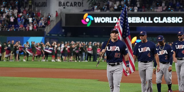 Mike Trout de los Estados Unidos lidera a sus compañeros mientras porta la bandera estadounidense antes de un partido contra Japón en el LoanDepot Park el 21 de marzo de 2023 en Miami, Florida. 