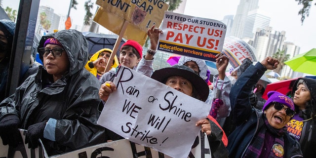Teachers Hilda Juarez, center, holds a soggy sign as teachers and SEIU workers and supporters demonstrate outside LAUSD headquarters on Wednesday, March 22, 2023, in Los Angeles, CA. 