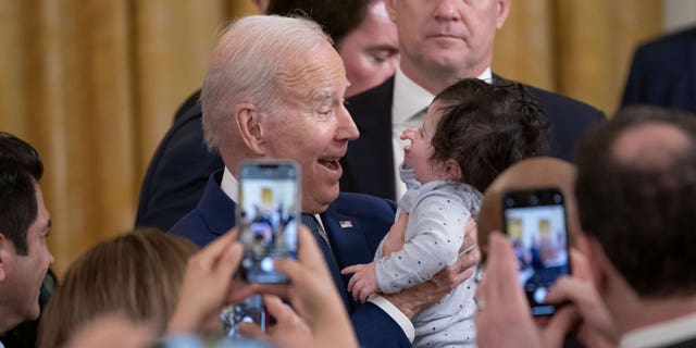 Presiden AS Joe Biden menggendong putra Perwakilan Jimmy Gomez, seorang Demokrat dari California, selama acara peringatan Undang-Undang Perawatan Terjangkau di Ruang Timur Gedung Putih di Washington, DC, AS, pada Kamis, 23 Maret 2023.