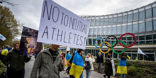 Ukrainians pass the International Olympic Committee (IOC) headquarters during a protest against the IOC's proposed roadmap to organize the return of Russian athletes to competition under a neutral flag, provided they do so. "Do not actively support the war in Ukraine" In Lausanne on March 25, 2023.