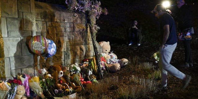 A man drops flowers to a makeshift memorial where balloons and teddy bears are left on the outside the Covenant School building at the Covenant Presbyterian Church, in Nashville, Tennessee, March 27, 2023.