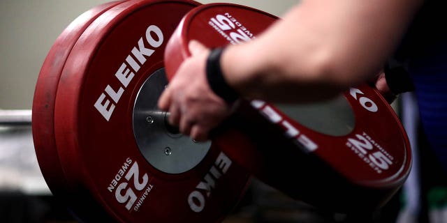 ARCHIVO - Nakatsuji Katsuhito de Japón coloca pesas en la barra mientras calienta en el área de entrenamiento antes de los hombres de hasta 107 kg durante el cuarto día de la Copa Mundial de Para Powerlifting en el Wythenshawe Forum el 28 de marzo de 2021 en Manchester, Inglaterra. 