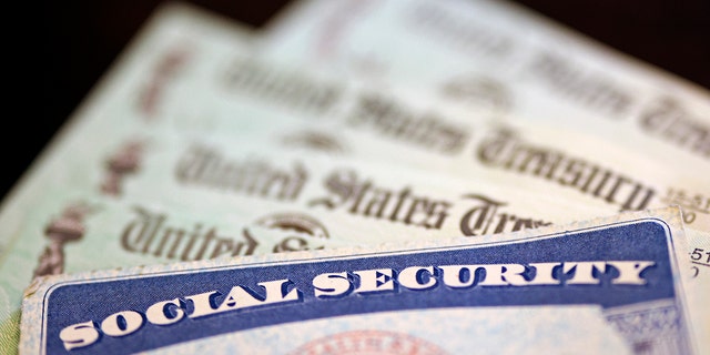 In this photo illustration, a Social Security card sits alongside checks from the U.S. Treasury on October 14, 2021 in Washington, DC.