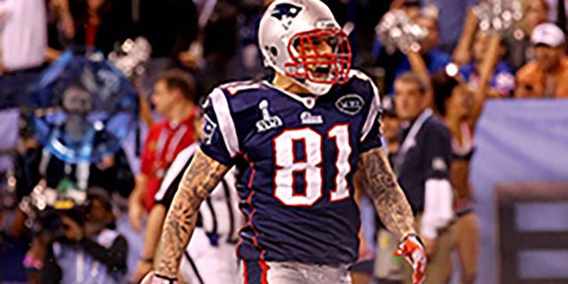 Aaron Hernandez #81 de los New England Patriots celebra después de atrapar un pase de touchdown de 12 yardas de Tom Brady #12 en el tercer cuarto contra Deon Grant #34 de los New York Giants en el Super Bowl XLVI en el Lucas Oil Stadium el 5 de febrero de 2012 en Indianápolis, Indiana.  