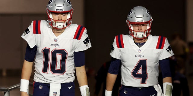 Mac Jones, left, and Bailey Zappe of the New England Patriots walk onto the field before the Cardinals game at State Farm Stadium on December 12, 2022 in Glendale, Arizona.