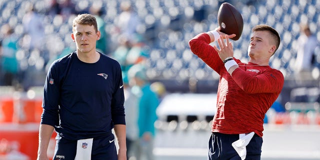 Bailey Zappe of the New England Patriots warms up as Mac Jones watches before the Miami Dolphins game at Gillette Stadium on Jan. 1, 2023, in Foxborough, Massachusetts.