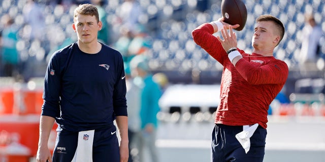 Bailey Zappe of the New England Patriots warms up as Mac Jones watches before the Miami Dolphins game at Gillette Stadium on Jan. 1, 2023, in Foxborough, Massachusetts.