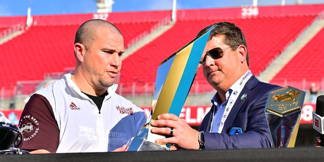 ReliaQuest CEO Brian Murphy, right, presents the trophy to Mississippi State Bulldogs head coach Zach Arnett after defeating the Illinois Fighting Illini 19-10 in the ReliaQuest Bowl at Raymond James Stadium on January 2, 2023 in Tampa, Florida.