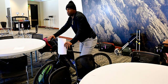 Colorado Buffaloes head football coach Deion Sanders rides a bicycle at a press conference on National Signing Day on February 1, 2023.