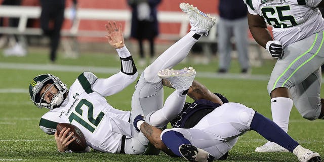 Quinten Dormady (12) of the Orlando Guardians is sacked by Charles Wiley (57) of the Houston Roughnecks at TDECU Stadium Feb. 18, 2023, in Houston.