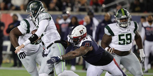 Quinten Dormady (12) of the Orlando Guardians is sacked by Charles Wiley (57) of the Houston Roughnecks at TDECU Stadium Feb. 18, 2023, in Houston.